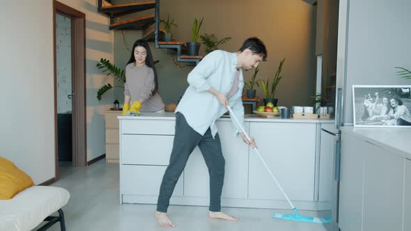 Beautiful Young Couple Doing Cleanup in Kitchen Washing Floor and Furniture