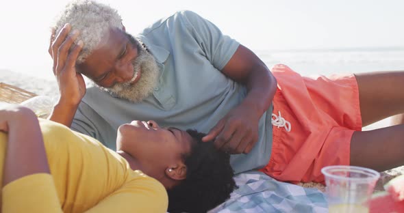 Happy african american couple having picnic on sunny beach