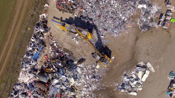 Aerial top-down shot of claw loader handling recyclable materials into trash compactor