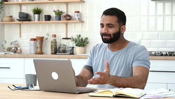 Angry Annoyed Indian Man Freelancer Manager Sits at Kitchen Emotionally Yells at a Laptop During