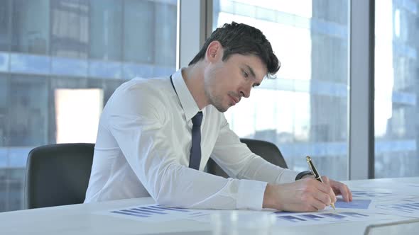 Young Businessman Working On Project Documents on Office Desk
