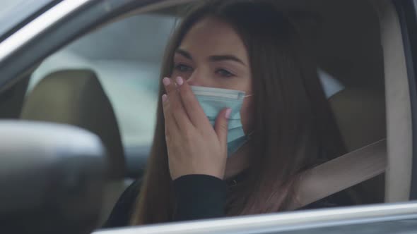 Close-up of Coughing Young Woman Sitting on Driver's Seat Wearing Protective Mask
