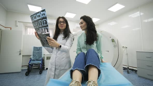Woman doctor radiologist explains good results of CT scanning for young female