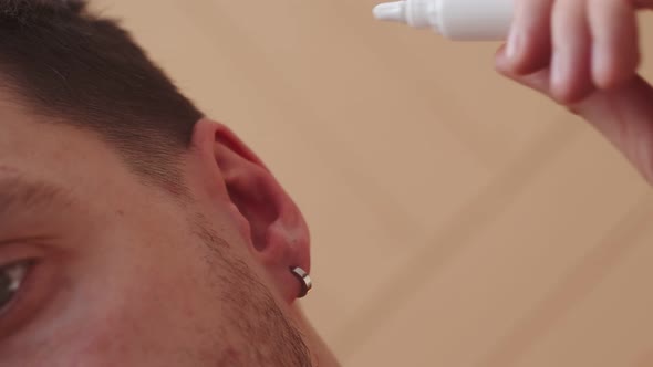 Closeup of Mans Ear in Which Medicine is Dropped From Bottle
