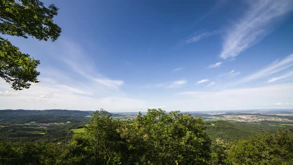 Timelapse image of clouds in landscape. The clouds pass over the camera. In the foreground are green