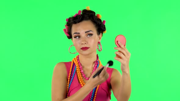 Girl with Curlers on Her Head in a Pink Dress Looking in Red Mirror and Powdered Her Nose with Big
