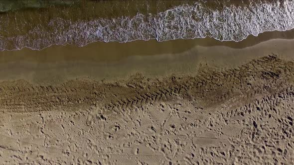 Aerial static view of the sea shore in a beach. Some dry white sands on one side and the small waves