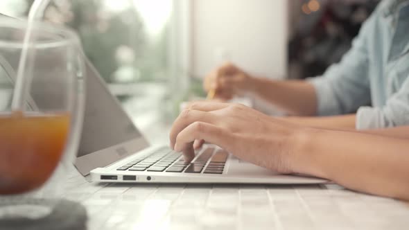 Young businesswoman working together using laptop sitting at cafe by window  and drinking coffee.