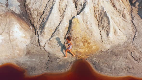 Aerial View of a Girl Who Climbs the Red Mountains in a Dress