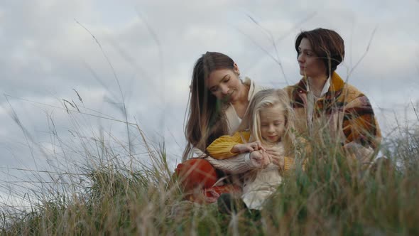 Two Loving Women Playing with Daughter on Nature