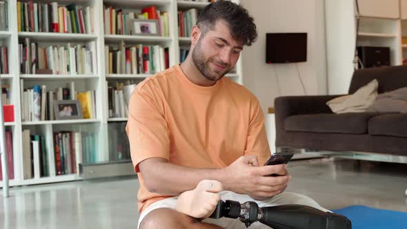 Happy Disabled Man with Prosthetic Leg Prosthesis Using Phone at Home