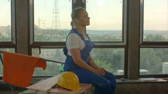 Attractive young builder on break. She is sitting and smiling