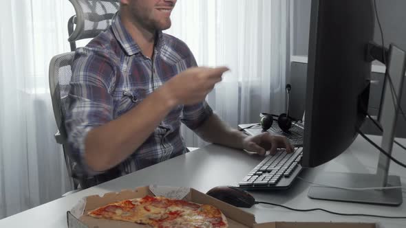 Handsome Man Enjoying Tasty Pizza While Working on a Computer