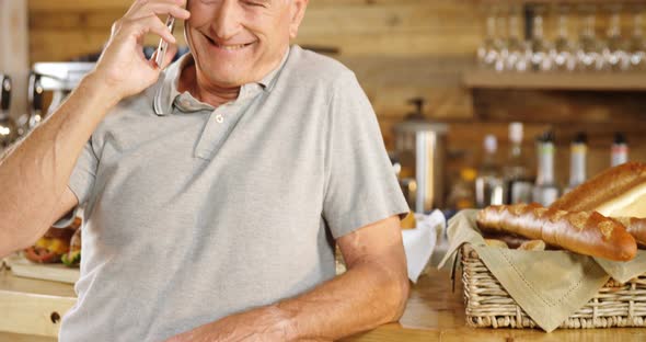 Senior man talking on the phone at cafe counter 