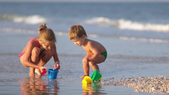 Older Sister Playing with Younger Brother Aground Near the Shore on Summer Vacation