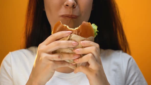 Woman Biting Unappetizing Hamburger, Dissatisfied With Food Quality, Closeup