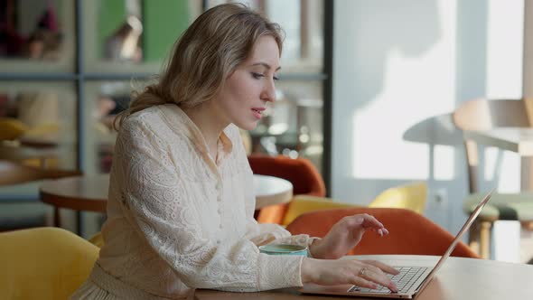 Side View of Confident Overworked Young Slim Woman Typing on Laptop Keyboard Sighing and Leaning on