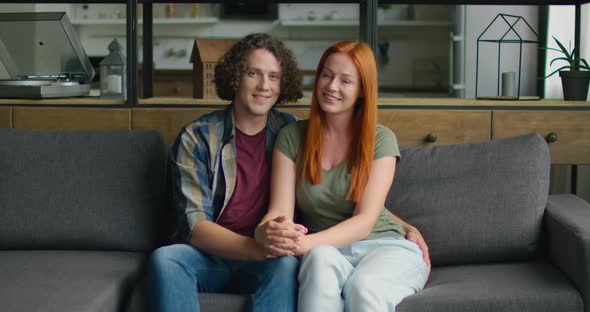 Portrait of Young Couple in Love, Sitting on Sofa at Home