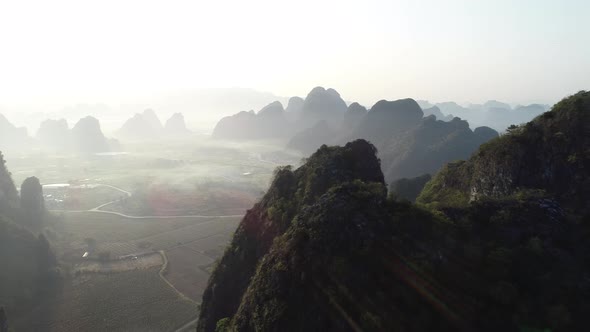 Aerial footage of beautiful sunrise over foggy karst mountain peak landscape