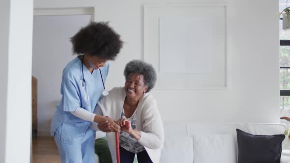 Caring african american female doctor helping senior african american female