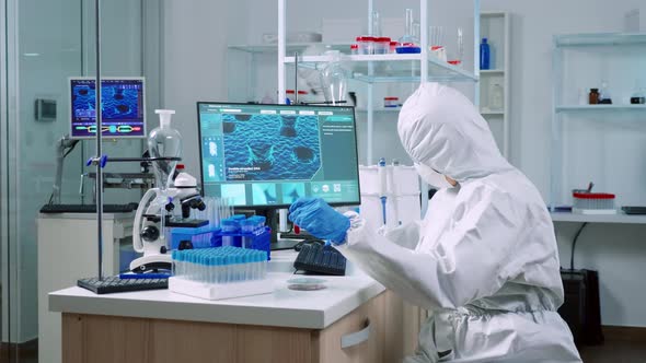 Doctor in Coverall Taking Blood Sample Tube From Rack with Machines