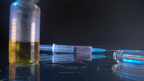 A Syringe with the Typed Medicine Is on a Glass Table. Next To It Is an Open Test Tube and a Vial