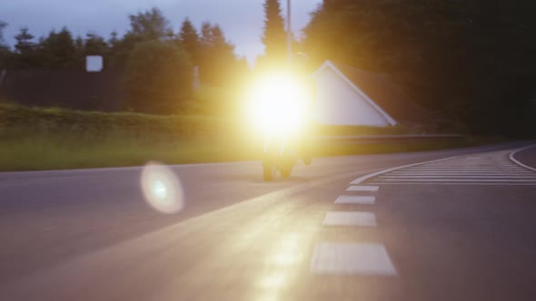 Motorcycle With Headlights Beaming Under the Dusk Skies Full Tracking Shot