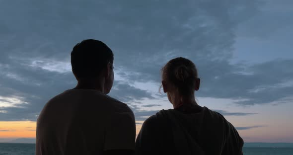 Loving couple looking at sea and sky in the evening