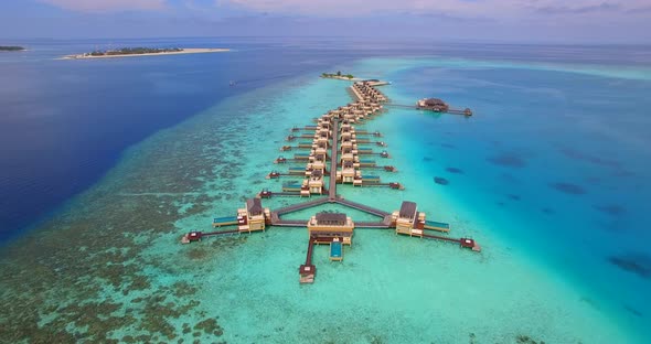 Aerial drone view of scenic tropical island and resort hotel with overwater bungalows in Maldives
