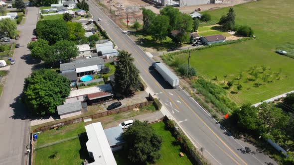 Aerial shot following a semi truck driving in a suburban area to its next delivery.
