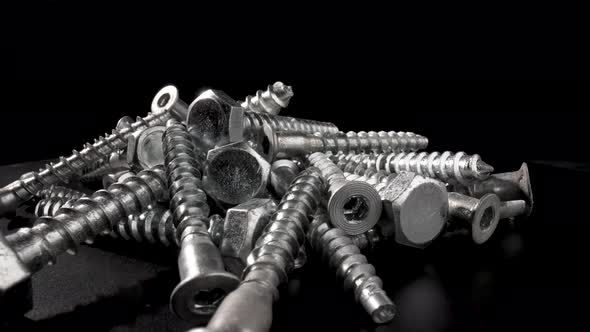 Pile of Steel Chrome Screws Rotating on Isolated Black Background