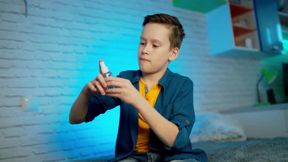 Boy using hand sanitizer alcohol spray rub for hands hygiene in home for preventive coronavirus