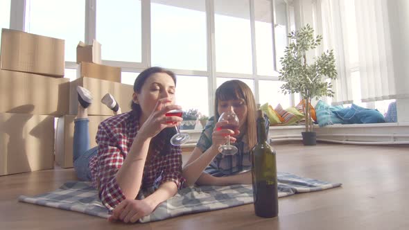 Same Sex Family Lying on the Floor and Drinking Wine Notes Moving Into a New Apartment