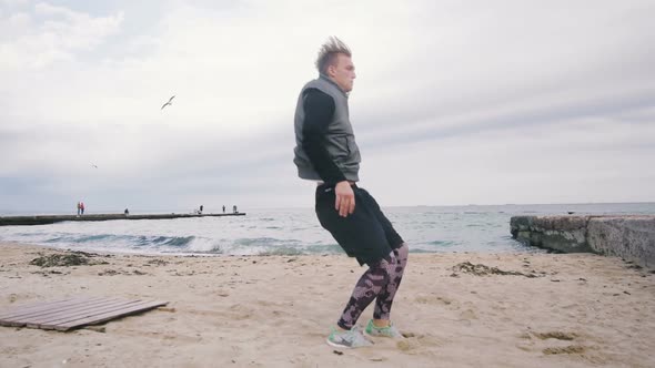 Young Man Doing Parkour Tricks on the Beach Near the Sea