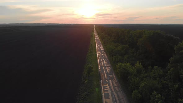 Straight Wet Lonely Road at Sunset After Rain. Perspective View of the Road.