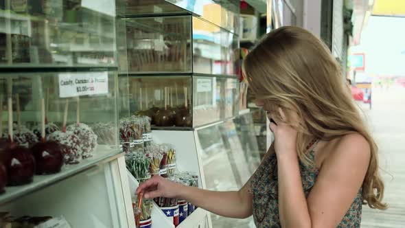 Girl on cellphone by confectionery shop