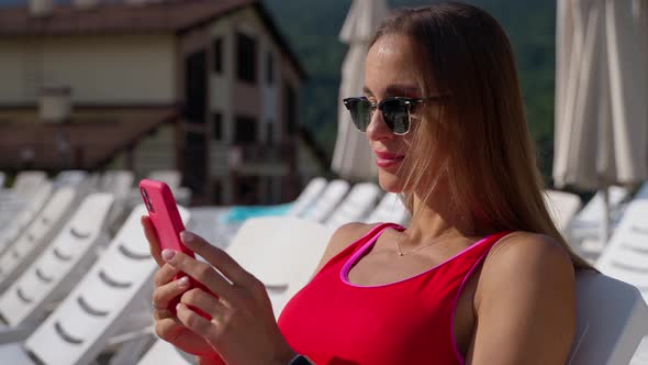 Hotel Guest Relaxing By the Pool with Cellphone