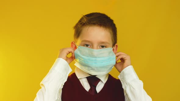 Positive Caucasian schoolboy 7-9 years old takes off his medical protective mask and smiles