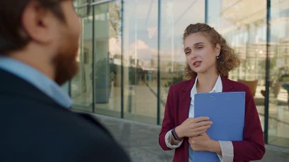 Back View of Businessman Talking To Elegant Female Manager Standing Outdoors