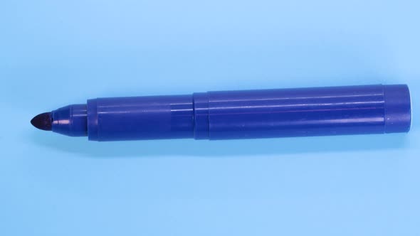 Blue marker pen rotating on blue surface background, macro shot close up view detail.