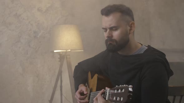 Young Man Playing Guitar in the Room