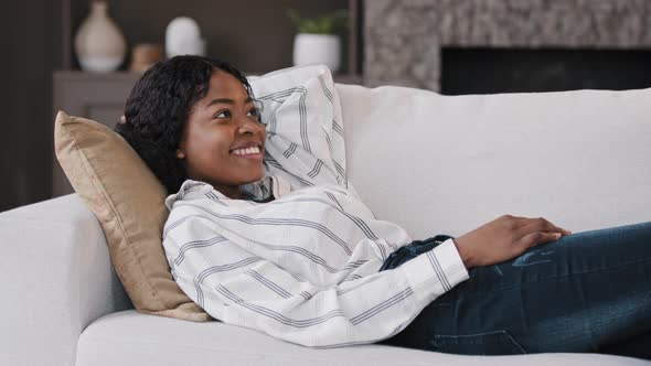 Happy Relaxed African American Woman Rest Lounge Lying on Couch Enjoy Peaceful Mood Weekend Casual