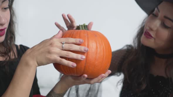Two Women Wearing Witch Costume For Halloween Touching And Feeling Pumpkin