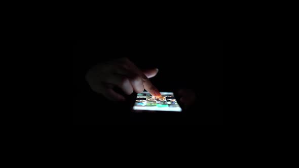 Person Hands Checking Cellphone. Close Up. Black Background