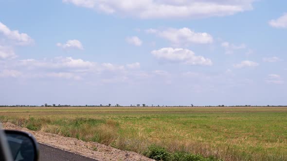 Side View From an Open Window of Car on Field Sky Clouds While Driving