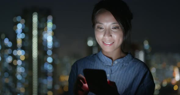 Woman look at cellphone with the building background at night