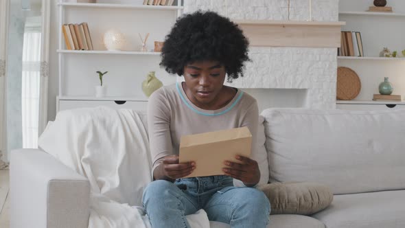 African Woman Opens Envelope Takes Out Paper Reading Notification Feels Frustrated and Shocked