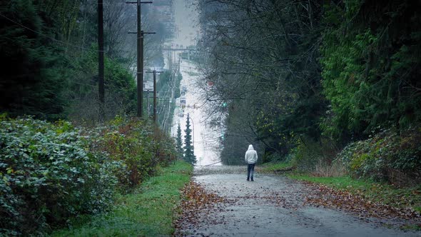 Man Walking Down Hill With Road In Distance
