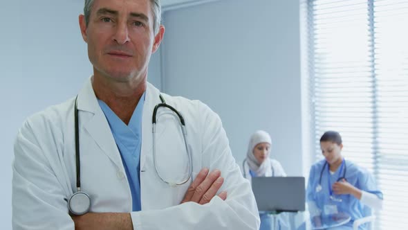 Close-up of Caucasian male doctor standing with arms crossed in hospital