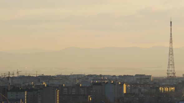 Urban Landscape with Distant Highrise Buildings Under Construction and Moving Tower Cranes Against